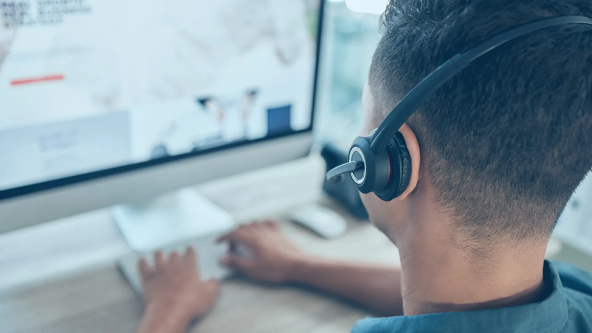 Figura di spalle con cuffia davanti a un monitor